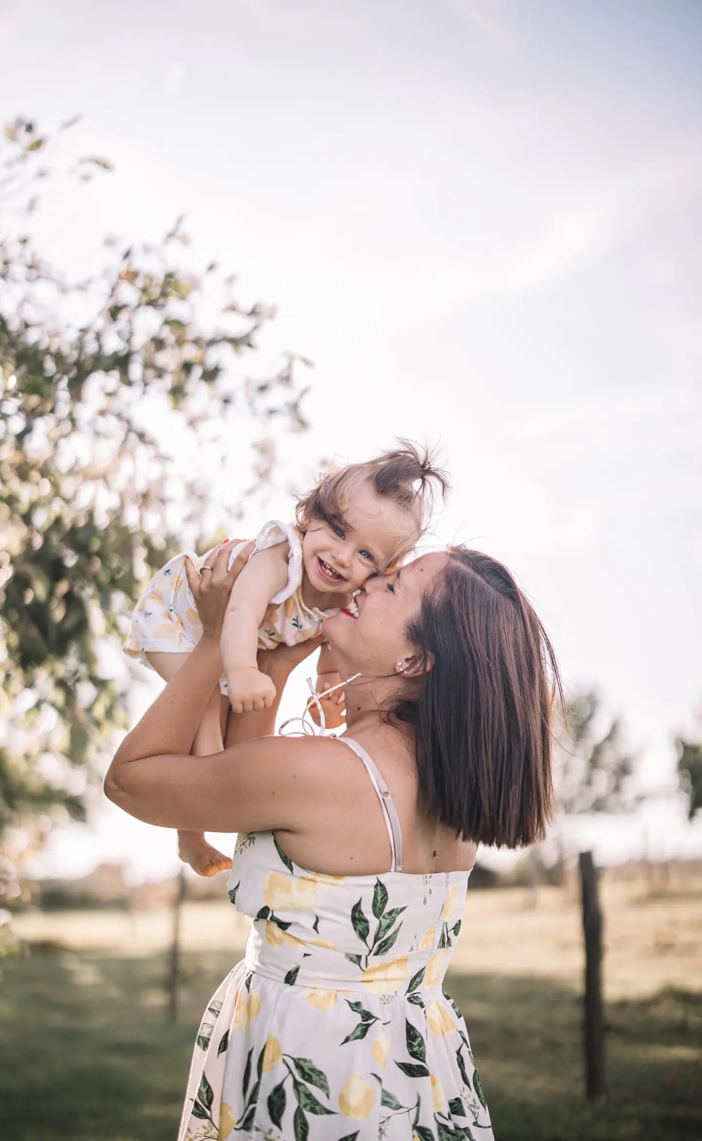Édesanya a levegőbe emeli nevető kislányát nyári fotózáson