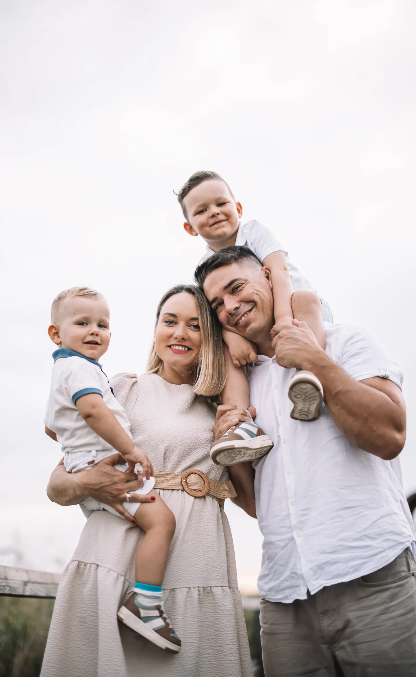 Négyfős család szabadtéri portréja, kisfiú az apukája vállán