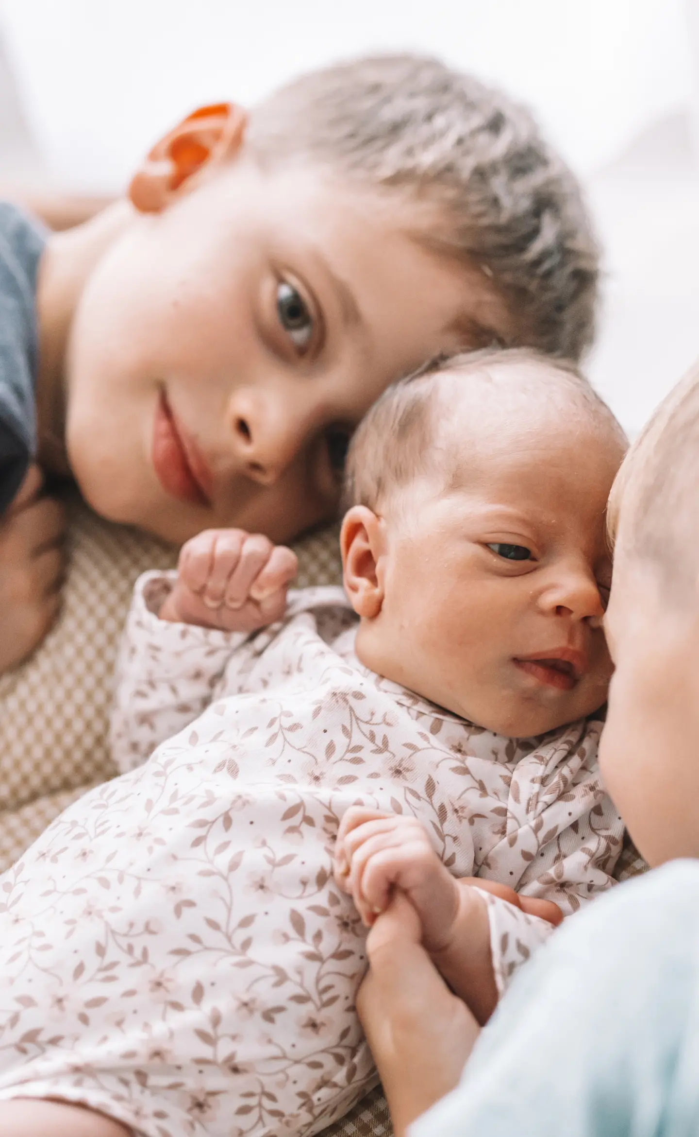 Újszülött baba és testvérei meghitt pillanatban, otthoni fotózáson