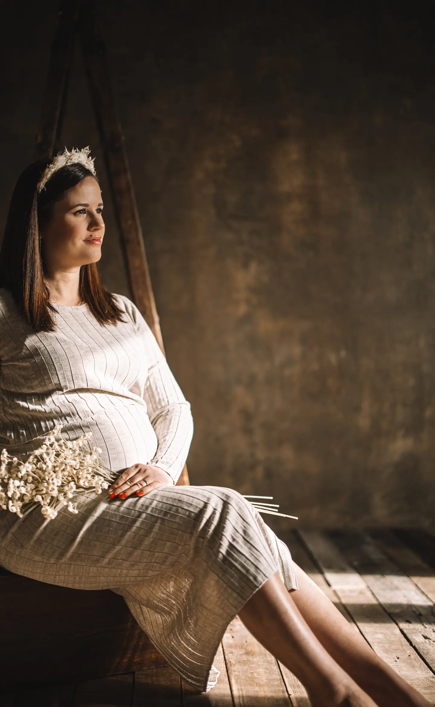 Kismama stúdióban ülve, természetes fényben, virágcsokorral