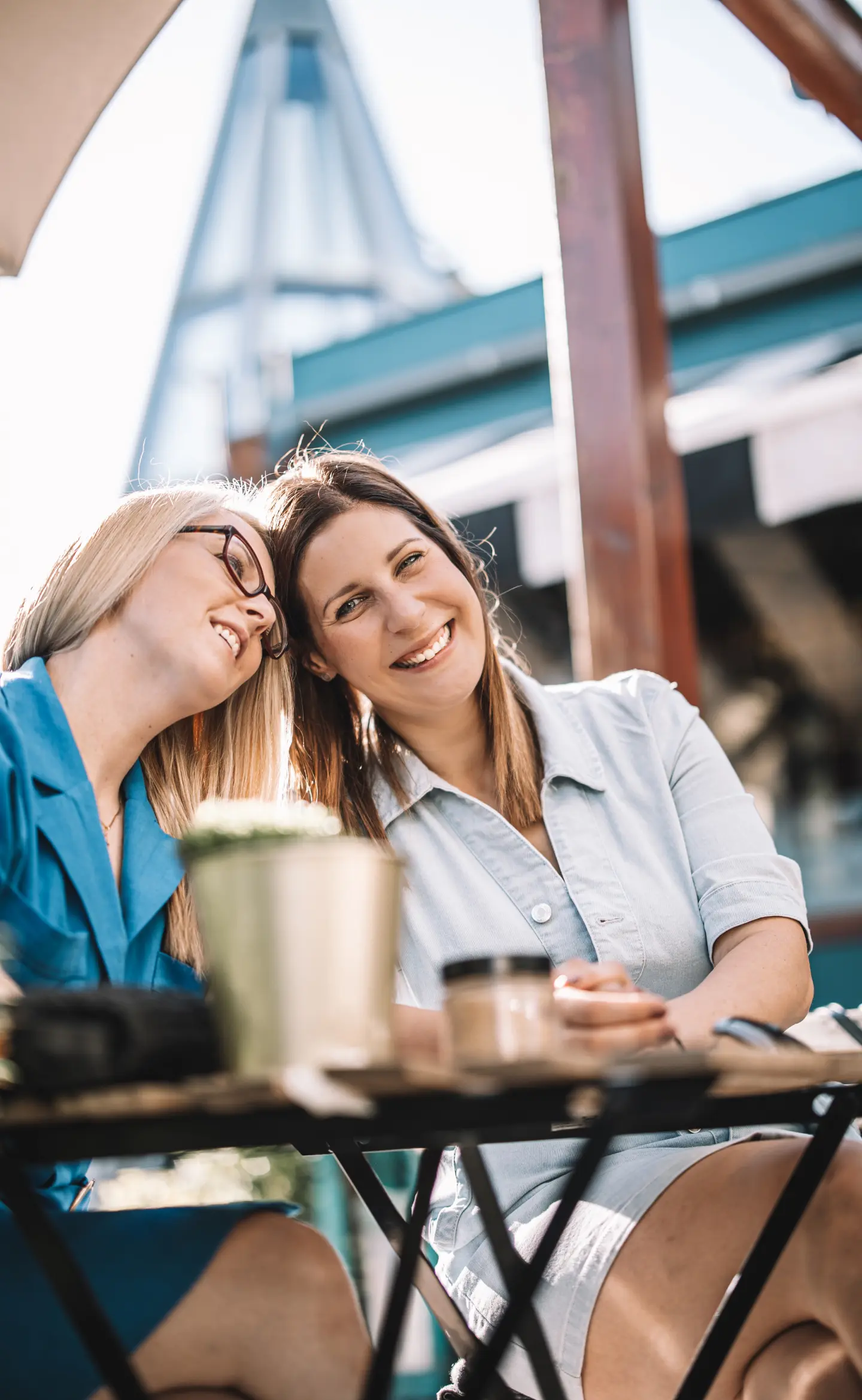 két barátnő egy kávézóban, ahogy egymásnak nyomják a fejüket, közben mosolyognak, portré fotózás