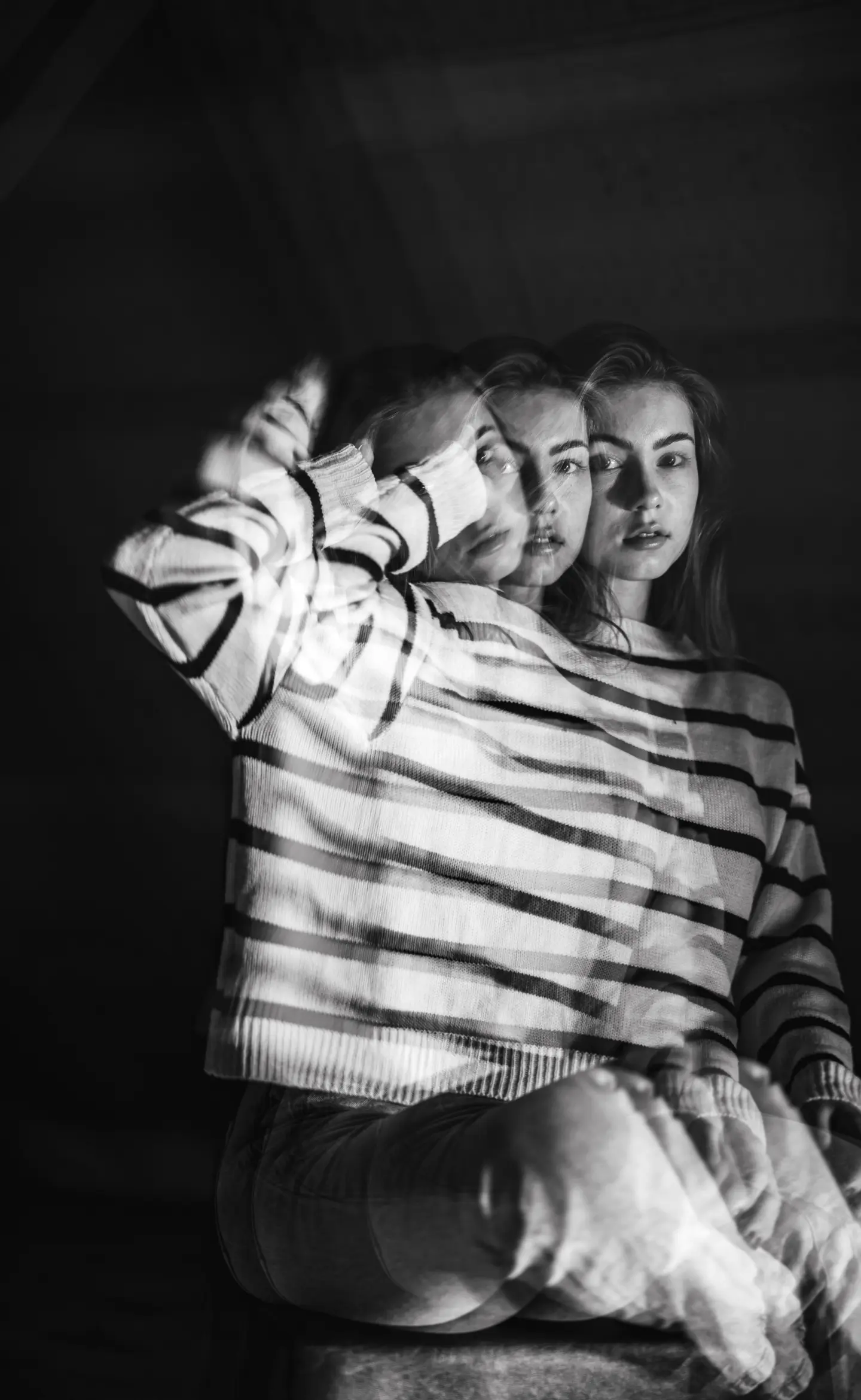egy lány fehér-fekete csíkos pulóverben, olyan hatás van a képen, mintha elmozdult volna a lány, ezért 3 alakban jelenik meg a képen, fekete-fehér a kép, portré fotózás