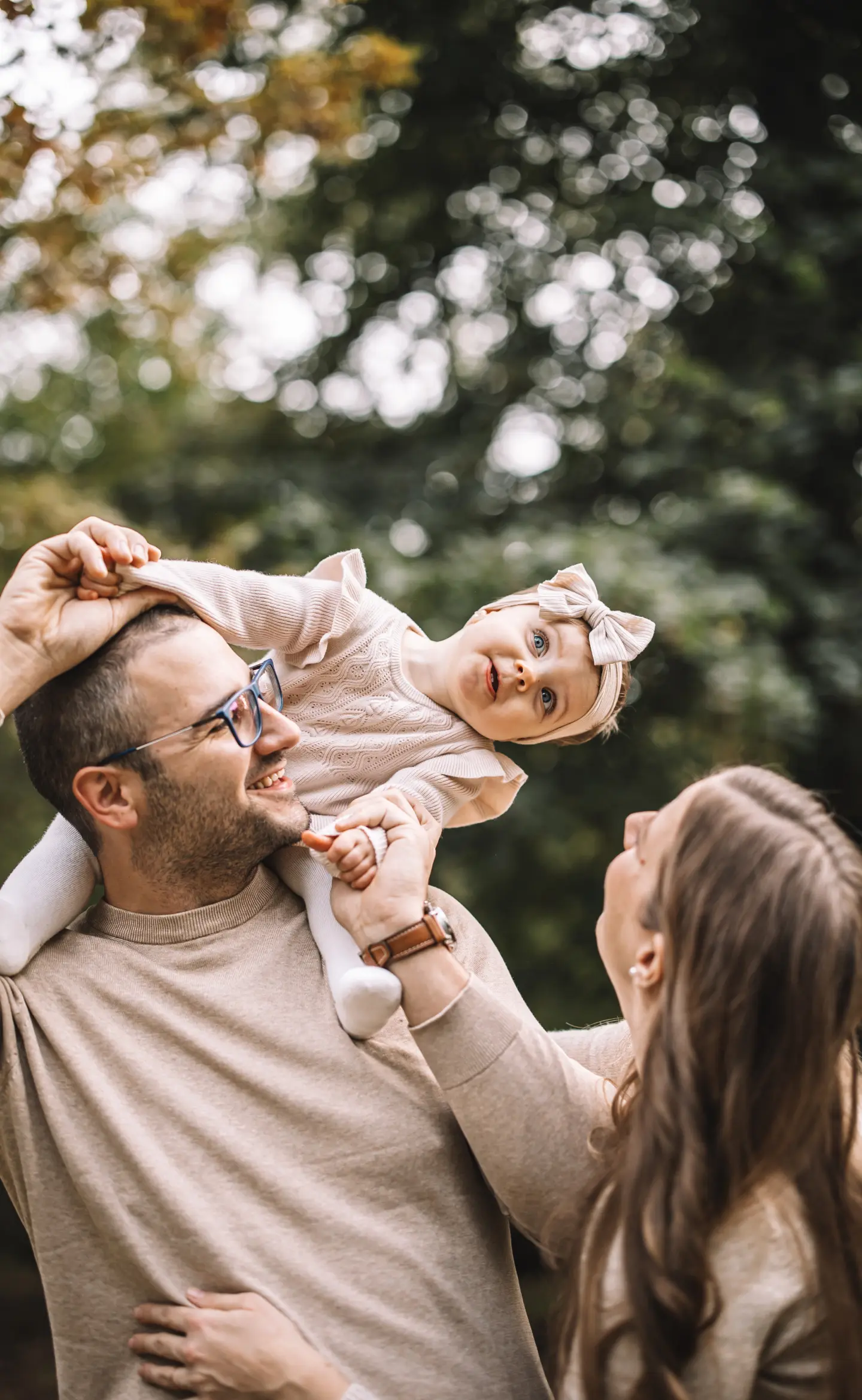 Kislány nevet a szülei között, miközben az apukája a nyakában tartja