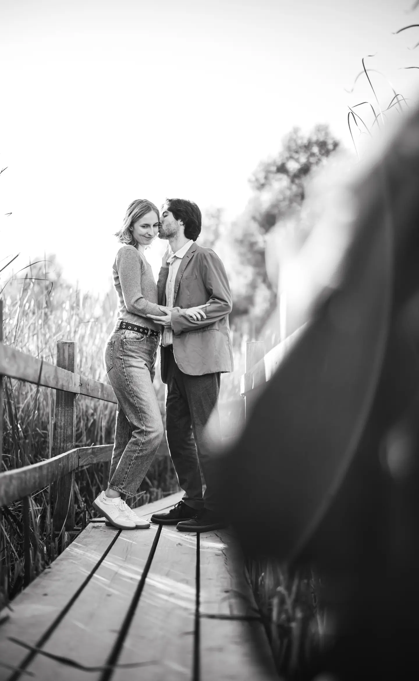 Pár öleli egymást egy pallón, természetes környezetben, fekete-fehér fotó