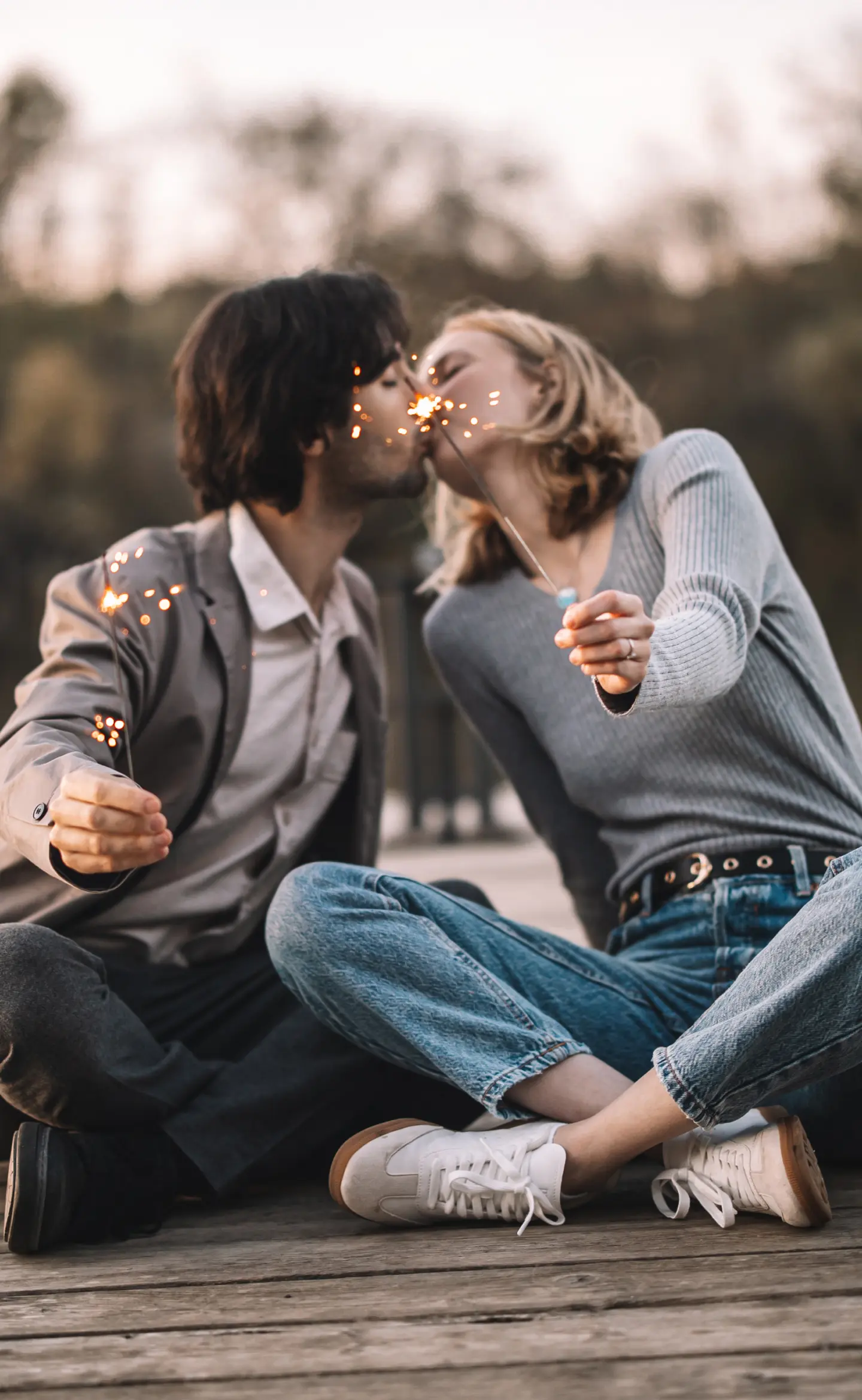 Fiatal pár csókolózik csillagszóróval a kezükben, stégen ülve