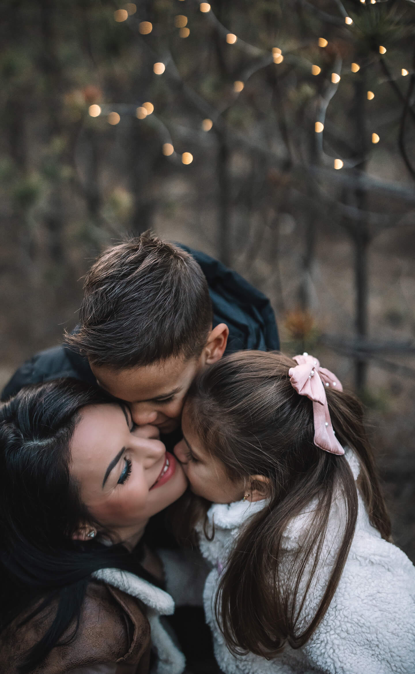 Édesanya ölelésében egy kisfiú és egy kislány, bensőséges családi pillanat az erdőben