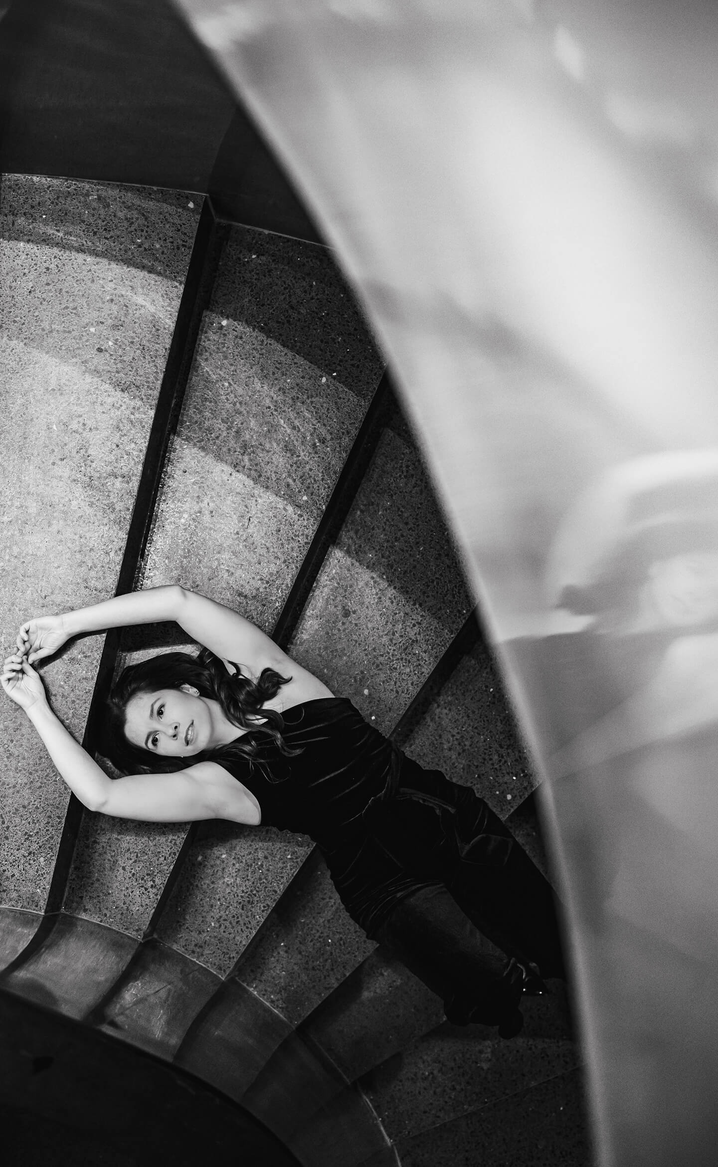Fiatal nő spirállépcsőn fekve, művészi fekete-fehér portréfotón